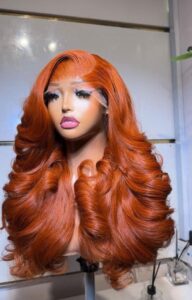 22-inch layered Cajun Ginger Vietnam Bounce Virgin human hair wig with a 5x5 lace closure styled in voluminous barrel curls.