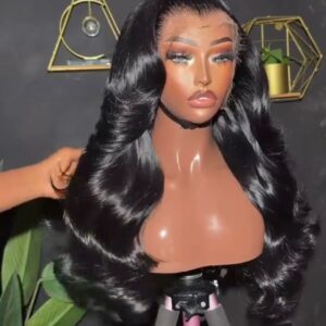 26-inch natural black raw Vietnamese wavy human hair wig featuring voluminous Hollywood body waves and layered face-framing cuts on a 13x4 Swiss frontal.