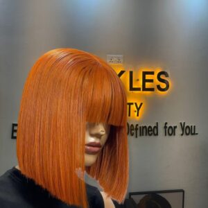 10-inch Super Double Drawn Cajun Orange Vietnamese Bone Straight human hair bob wig with full eye-skimming fringe bangs.